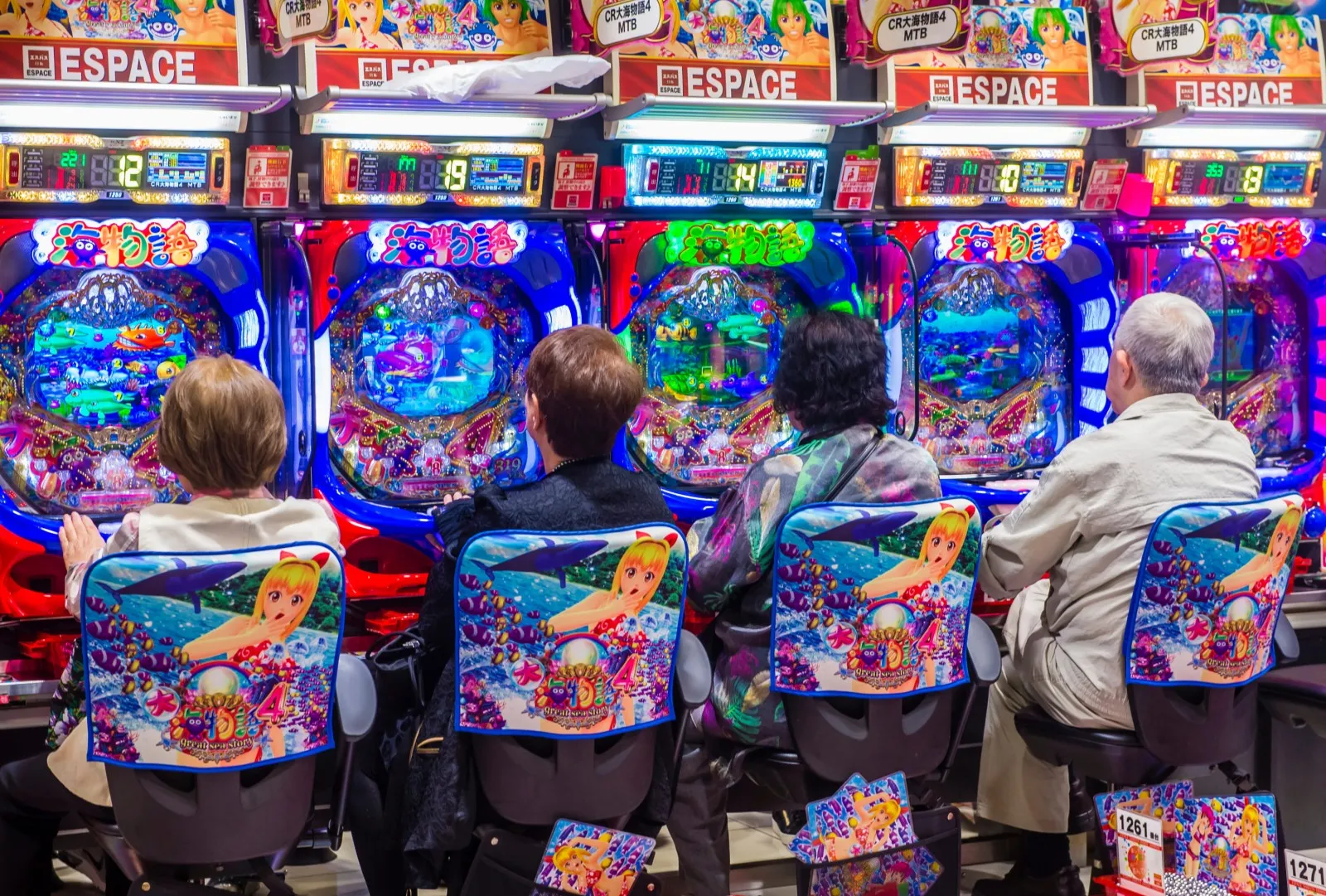 Visitors seated in front of a row of colourful pachinko machines